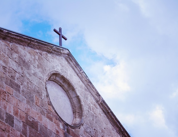 Foto detalle de una cruz de iglesia bajo un cielo nublado en tono vintage