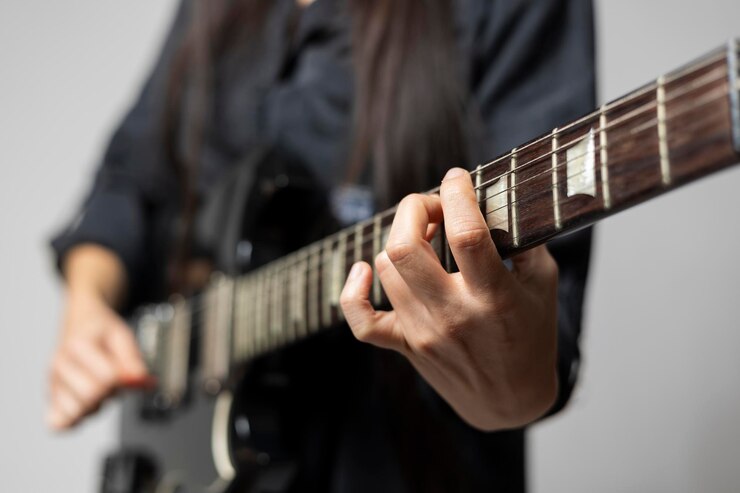 Foto detalle de las manos de una mujer guitarrista mientras toca unos acordes en la guitarra eléctrica detalle de las manos de una mujer guitarrista mientras toca unos acordes en la guitarra eléctrica