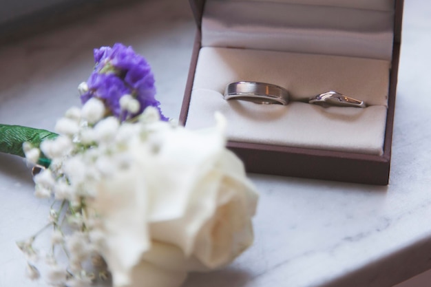 Detalle del día de la boda Los anillos de boda y la flor del ojal juntos