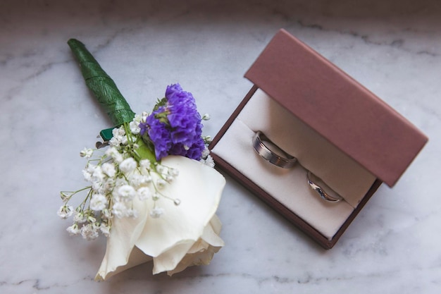 Detalle del día de la boda Los anillos de boda y la flor del ojal juntos