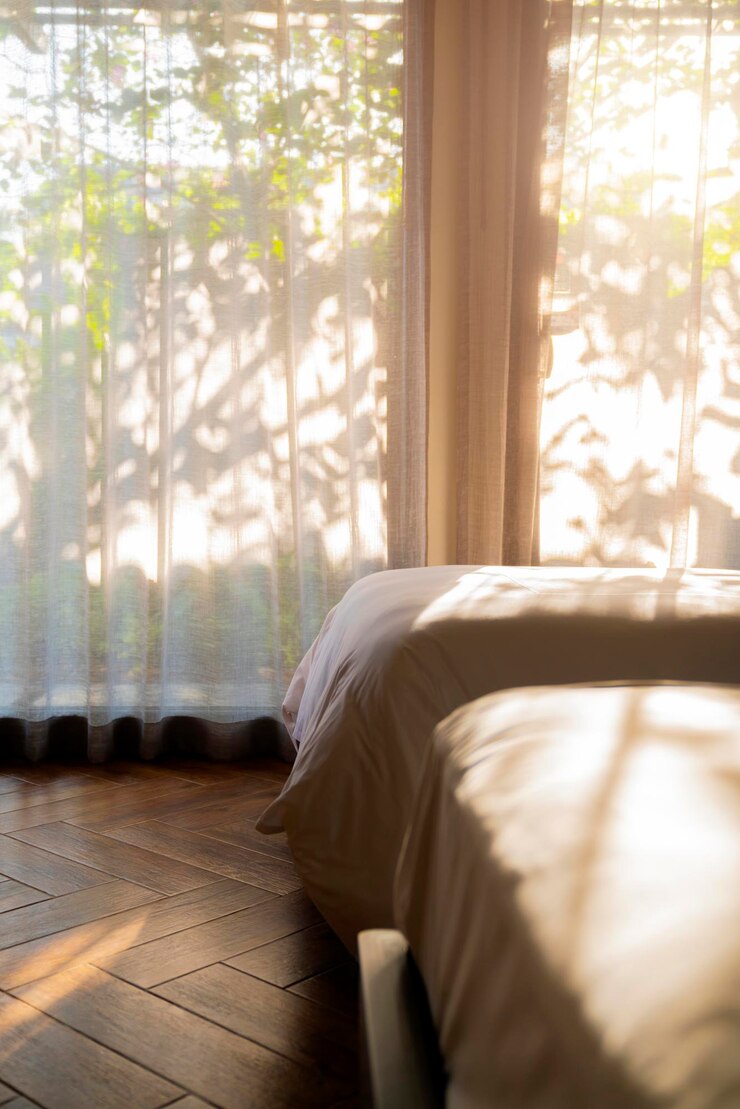Detalle de diseño de interiores de la casa concepto hermoso cerrar parte de la cama blanca suave con luz solar suave a través de la cortina de la ventana y hermoso jardín bokeh fuera de la silueta de la rama de un árbol fondo ideas para el hogar