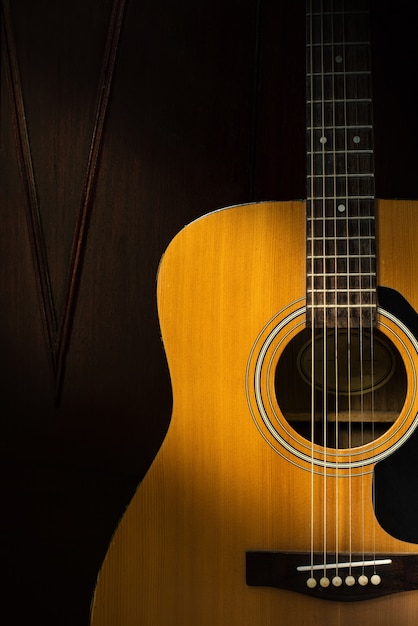 Detalle de la guitarra acústica en el cuarto oscuro con efecto de filtro retro