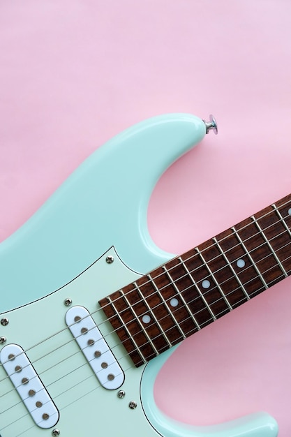 Detalle de guitarra eléctrica sobre una superficie rosa