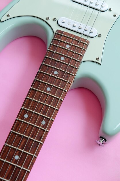 Foto detalle de guitarra eléctrica sobre una superficie rosa