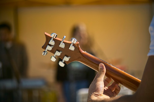 Foto detalle de la hoja y la mecánica de una guitarra eléctrica mientras toca en vivo en un concierto