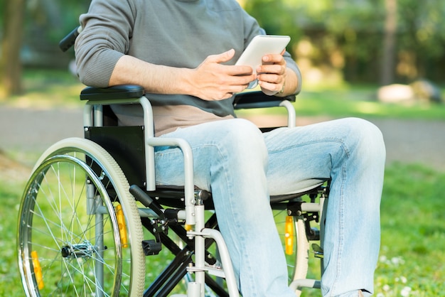 Detalle de un hombre discapacitado usando una tableta en un parque
