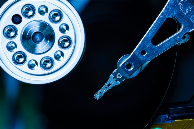 Detalle del interior de un disco duro con el cabezal de lectura en funcionamiento, imagen de luz azul