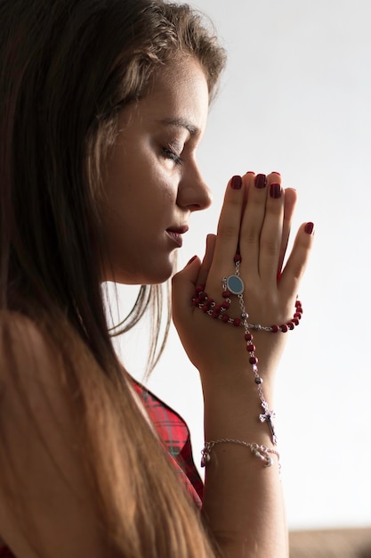 Foto detalle de una joven rezando el rosario.