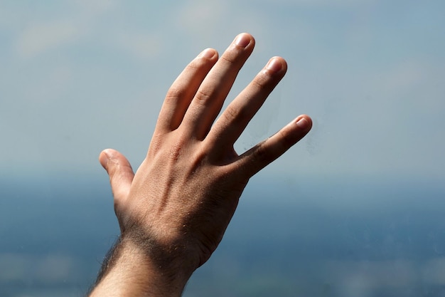 Detalle de la mano del hombre en el cristal de la ventana