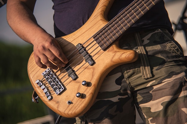 Detalle de la mano mientras toca un bajo acústico de madera en un concierto de rock