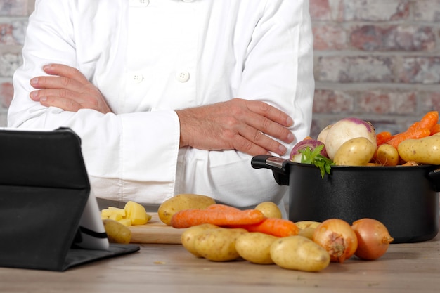 Detalle de manos del chef con tableta para cocinar