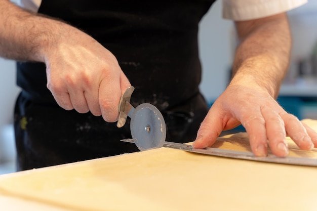 Detalle de las manos de un hombre cocinando croissants caseros midiendo el hojaldre y haciendo que los cortes funcionen en casa