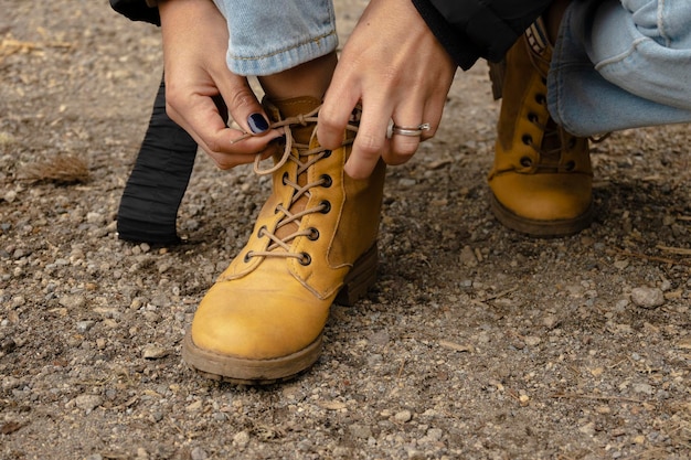 Detalle de las manos de la mujer atando los cordones de sus botas concepto de paseo por el bosque