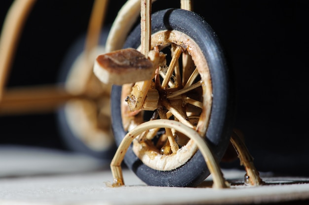 El detalle miniatura de la artesanía tiró de la bicicleta de madera en fondo negro. Plano macro de la rueda delantera.