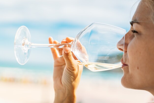 Detalle de una mujer bebiendo vino blanco al aire libre