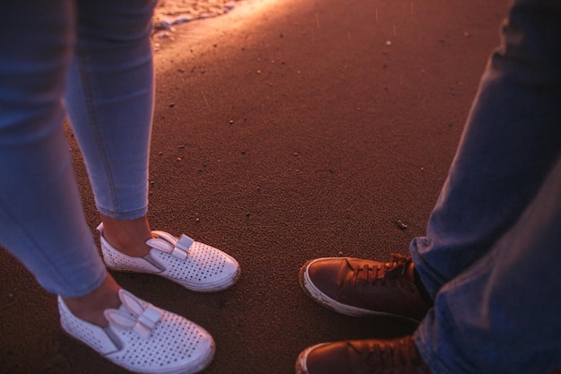 Foto detalle de pareja romántica caminando juntos por la playa de la puesta del sol hermosa puesta de sol y gotas de lluvia shjoes y arena closeup