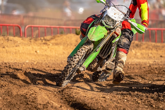 Detalle de la parte delantera de una bicicleta de motocross fuera de carretera que atraviesa una curva en terreno fangoso