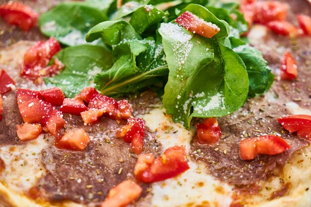 Detalle de pizza con tomate y albahaca