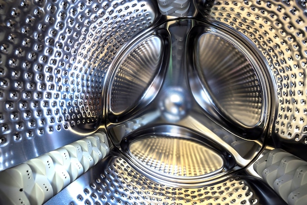 Detalle de primer plano, tambor inoxidable del interior moderno de la lavadora. Diseño de superficie brillante plata abstracta.