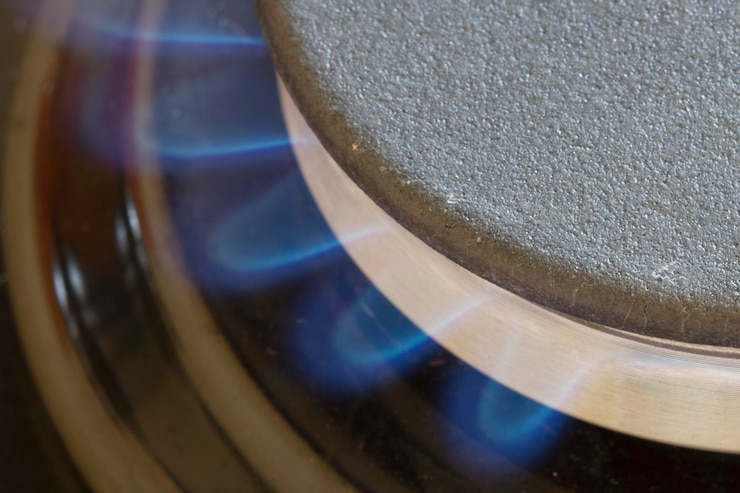 Foto detalle del quemador de gas con llama azul sobre un fondo oscuro