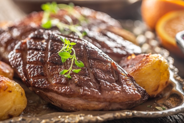 Foto detalle de sabrosas pechugas de pato asadas y patatas en un plato vintage.