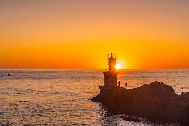 Detalle del sol detrás del faro al atardecer en el pueblo de Pasajes San Juan