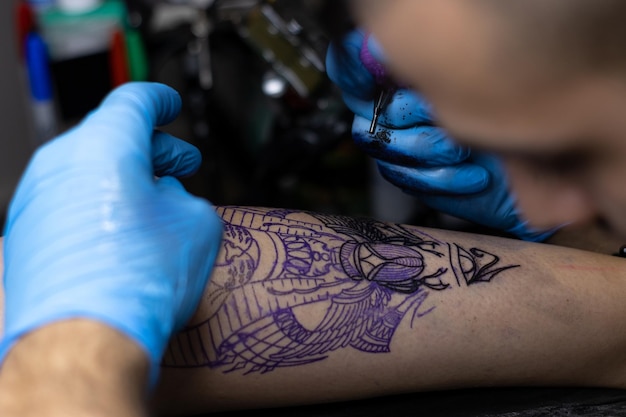 Detalle de un tatuador profesional irreconocible pasando y tatuando en su estudio