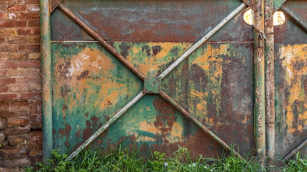 Detalle de una vieja puerta de metal oxidada pintada en colores verde y amarillo