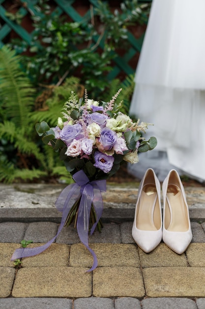 Detalles de la boda zapatos de novia clásicos y ramo de rosas de pie en el vestido de pf de fondo y