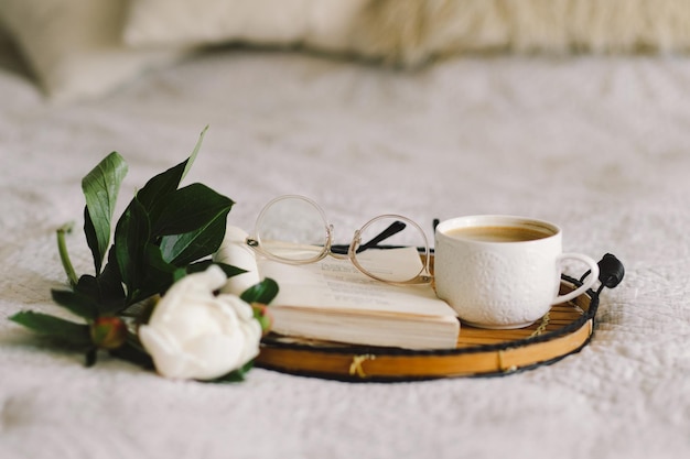 Detalles de bodegones en el interior de la sala de estar Libro abierto con vasos taza de café y ramo de flores de peonías rosas blancas Leer y descansar Hogar acogedor