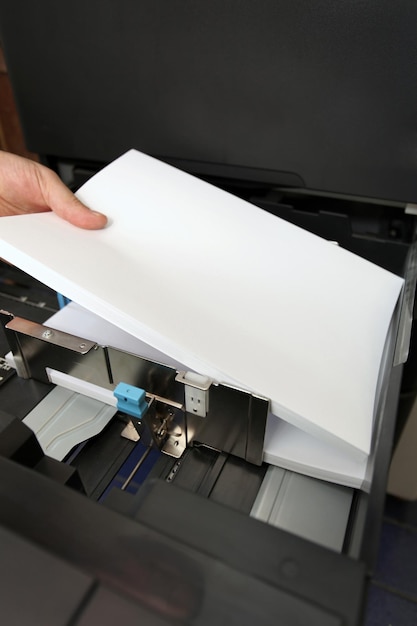 Foto detalles de la mano inserta un papel a4 en una copiadora láser