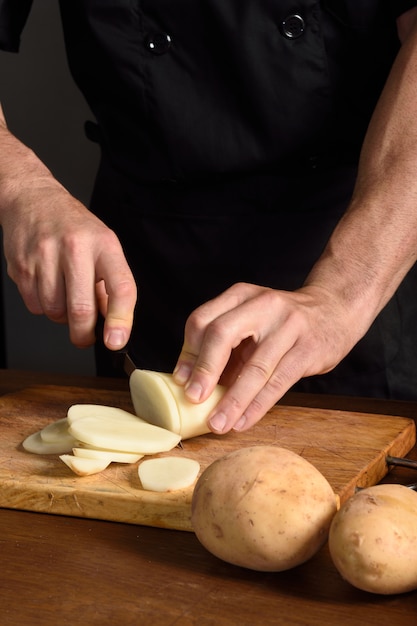 Detallle de un chef cortando patatas