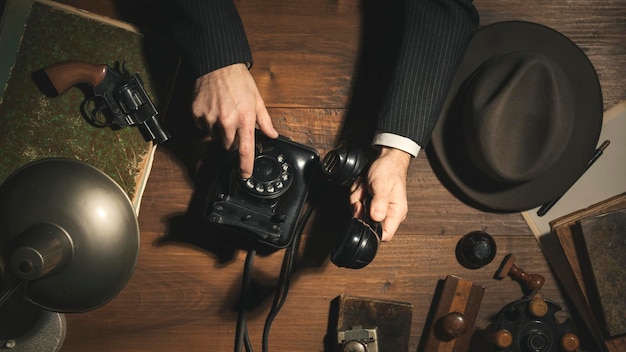 Detective negro al estilo de los años 50 haciendo una llamada telefónica a altas horas de la noche en el piso de oficina antiguo