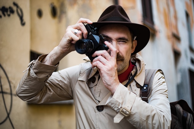 Detective tomando fotos en un barrio pobre con su cámara vintage