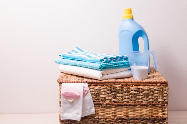 Detergente para ropa, gel de lavado y ropa en una canasta de mimbre