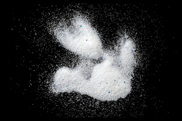 Foto detergente para ropa en polvo blanco, detergente en polvo aislado en la vista superior negra