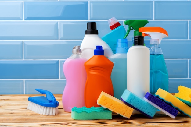 Detergentes domésticos y herramientas de limpieza contra el fondo de mosaico azul