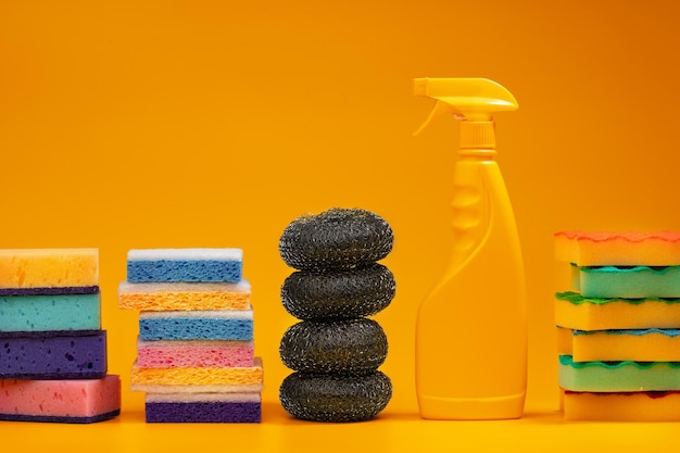Detergentes e esponjas de limpeza doméstica em fundo amarelo