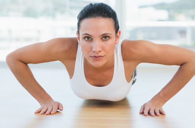 Determinada mujer hermosa haciendo flexiones en el gimnasio