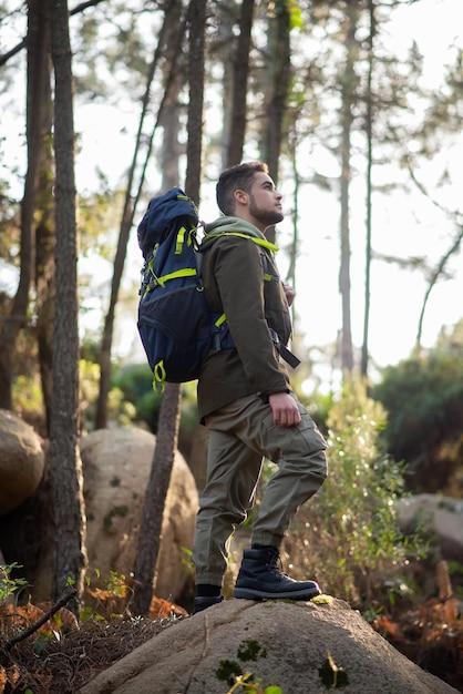 Determinado caminhante masculino na floresta. Homem com mochila com roupas casuais em pé na colina. Natureza, lazer, conceito de hobby