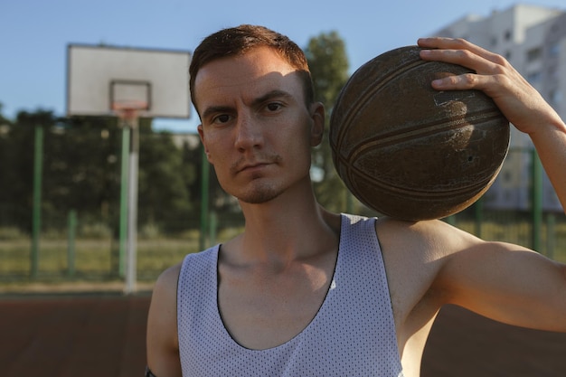 Foto determinado jugador de baloncesto masculino de pie con la pelota en la cancha urbana en la ciudad