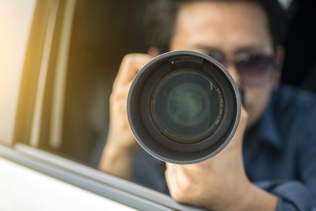 Detetive particular sentado dentro da câmera do carro com câmera slr