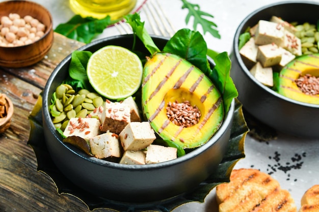 Detox-Buddha-Schüssel mit Avocado-Tofu-Käse, Leinsamen, Kürbiskernen und Spinat Das Konzept der diätetischen Ernährung auf Steinhintergrund