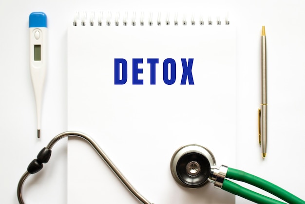 DETOX-Text in einem Notizbuch auf einem Schreibtisch und einem Stethoskop