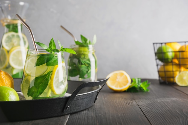 Detoxwasser oder -limonade mit Zitronenminze, Zitronensäure im Glas auf Holztisch und grauem Hintergrund.