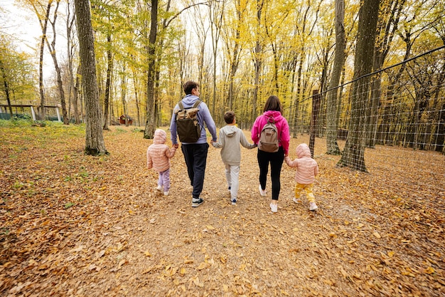 Detrás de la familia con niños en un paseo por el bosque de otoño