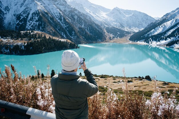 Detrás de la imagen de un hombre tomando una foto de un lago de montaña