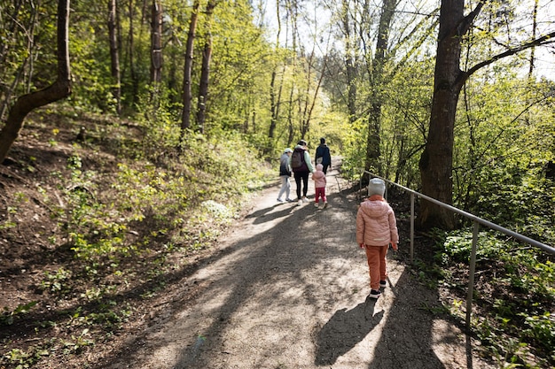 Detrás de la madre con niños pequeños caminando al aire libre en la naturaleza primaveral