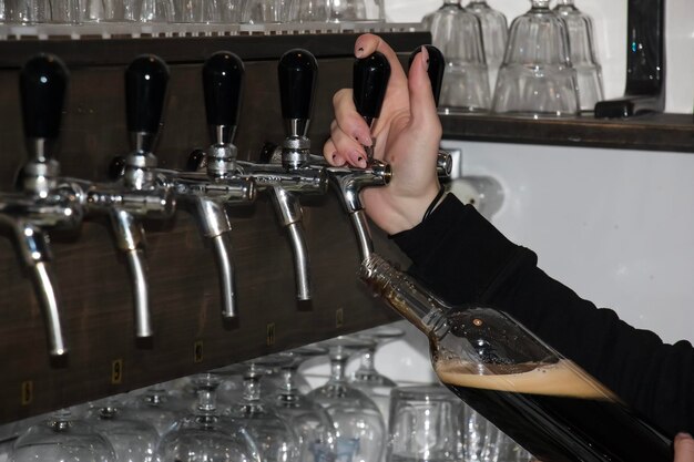 Foto detrás del mostrador las manos de las mujeres hermosa y fácilmente verter cerveza en una botella