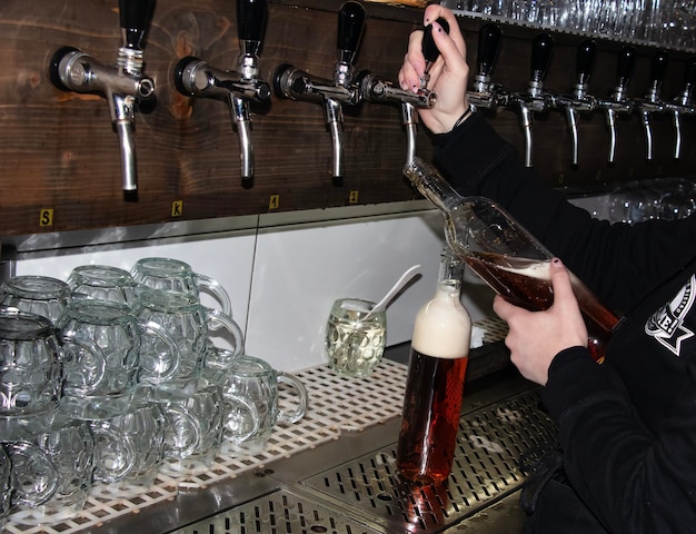 Foto detrás del mostrador las manos de las mujeres hermosa y fácilmente verter cerveza en una botella